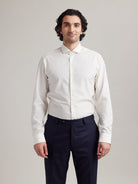 Man wears white merino shirt with long sleeves and spread collar with white buttons