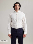 Man wears white merino shirt with long sleeves and spread collar in slim fit
