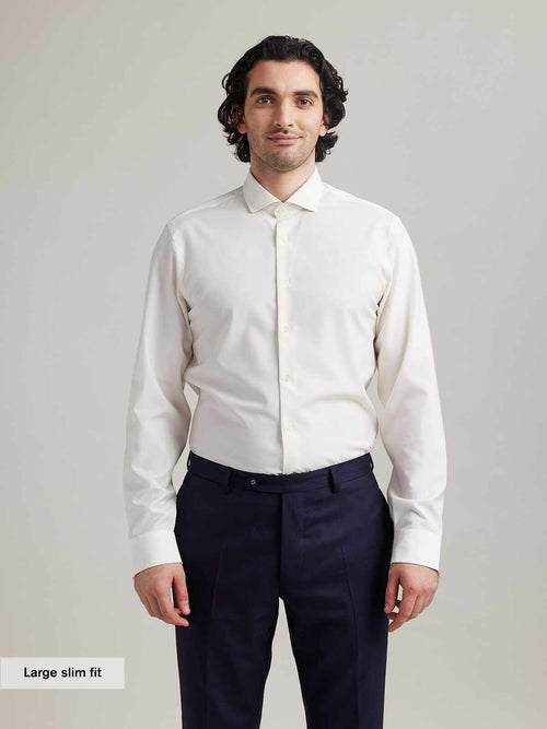 Man wears white merino shirt with long sleeves and spread collar in slim fit