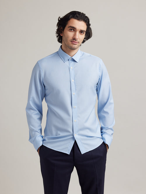 Man wears a light blue merino wool shirt in 100% superfine merino wool. Made in Europe.