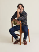 Man wears a merino wool flannel shirt with grey brown checked plaid on a dark jeans with boat shoes