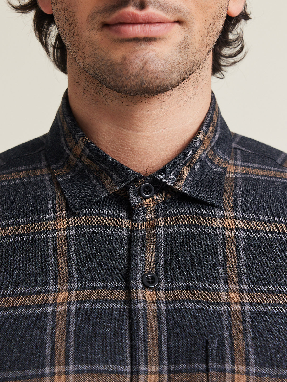 Close up of man wearing a merino wool shirt from Wolk with corozo buttons in grey brown plaid pattern