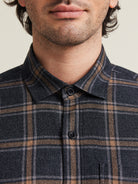 Close up of man wearing a merino wool shirt from Wolk with corozo buttons in grey brown plaid pattern