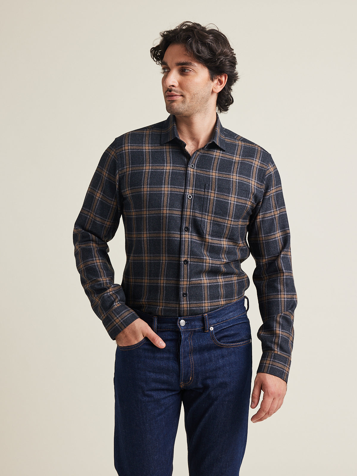 Man wears a merino wool flannel shirt from Wolk in grey brown plaid pattern with chest pocket