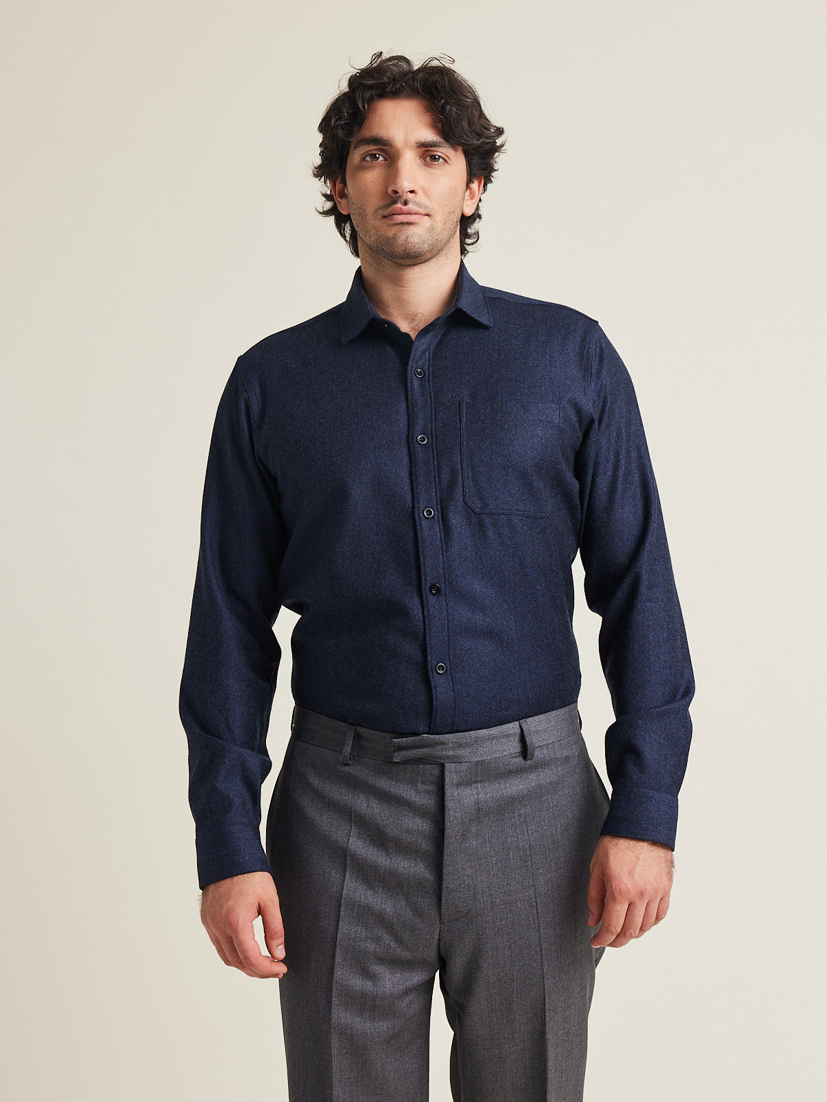 Man wears a merino flannel shirt in navy color with chest pocket on grey trousers