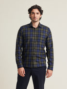 Man wears merino wool flannel shirt in blue green check pattern with chest pocket