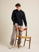 Man holds a vintage chair from Meteor Gallery. He wears a black wide boxy fit merino wool shirt from Wolk.