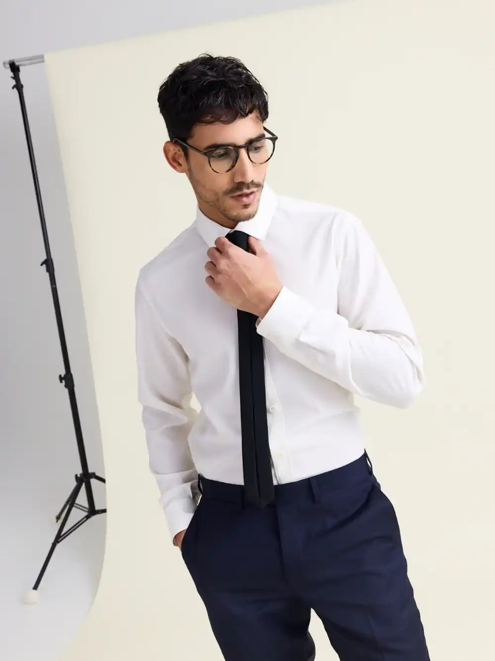 Man wearing a white merino wool shirt with black tie on navy trousers