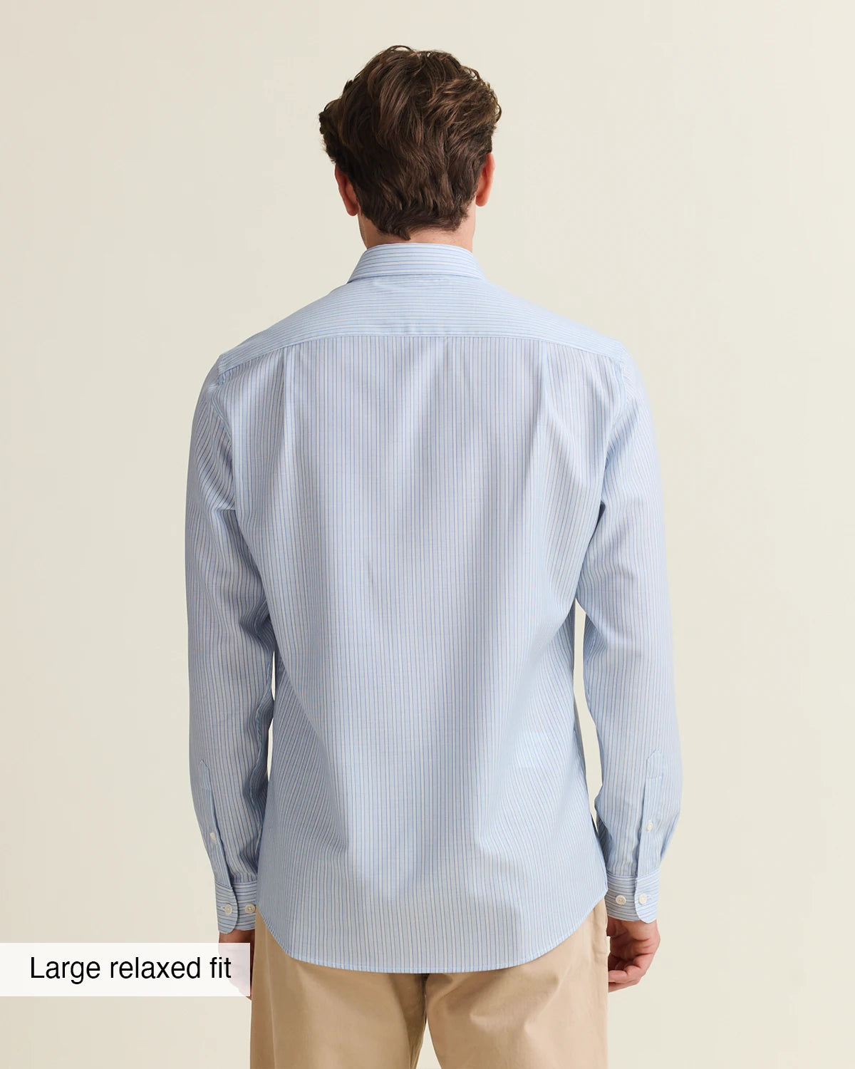 Backside of a Man wearing a light blue striped merino shirt on a beige pants untucked in size large relaxed