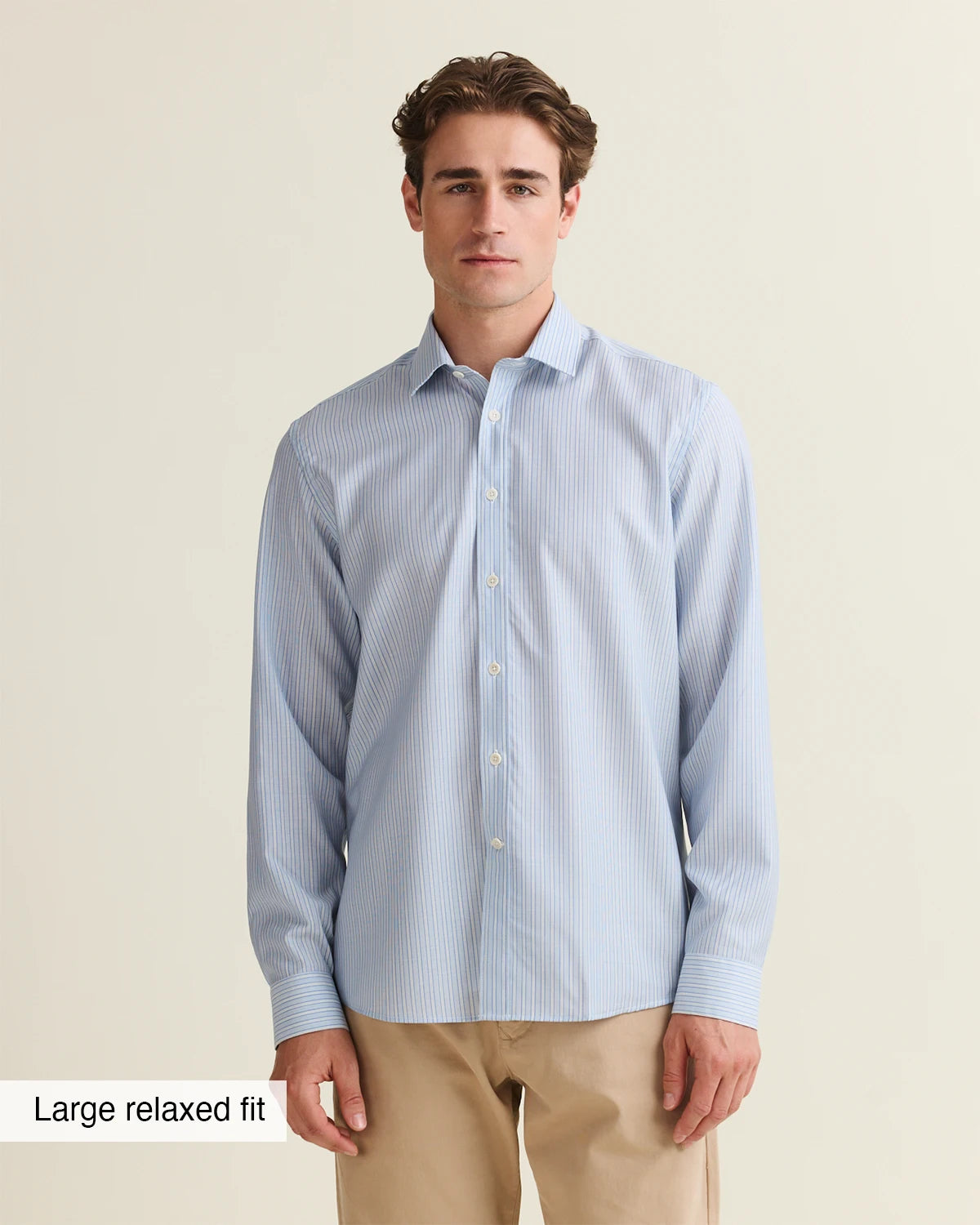 Man wearing a light blue striped merino shirt from Wolk in large relaxed fit label on a beige background