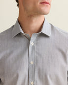 Close-up of a man wearing a navy striped merino shirt with a neutral background