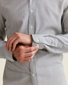 Close-up of the cuffs of a merino shirt worn by a person in navy and white striped pattern
