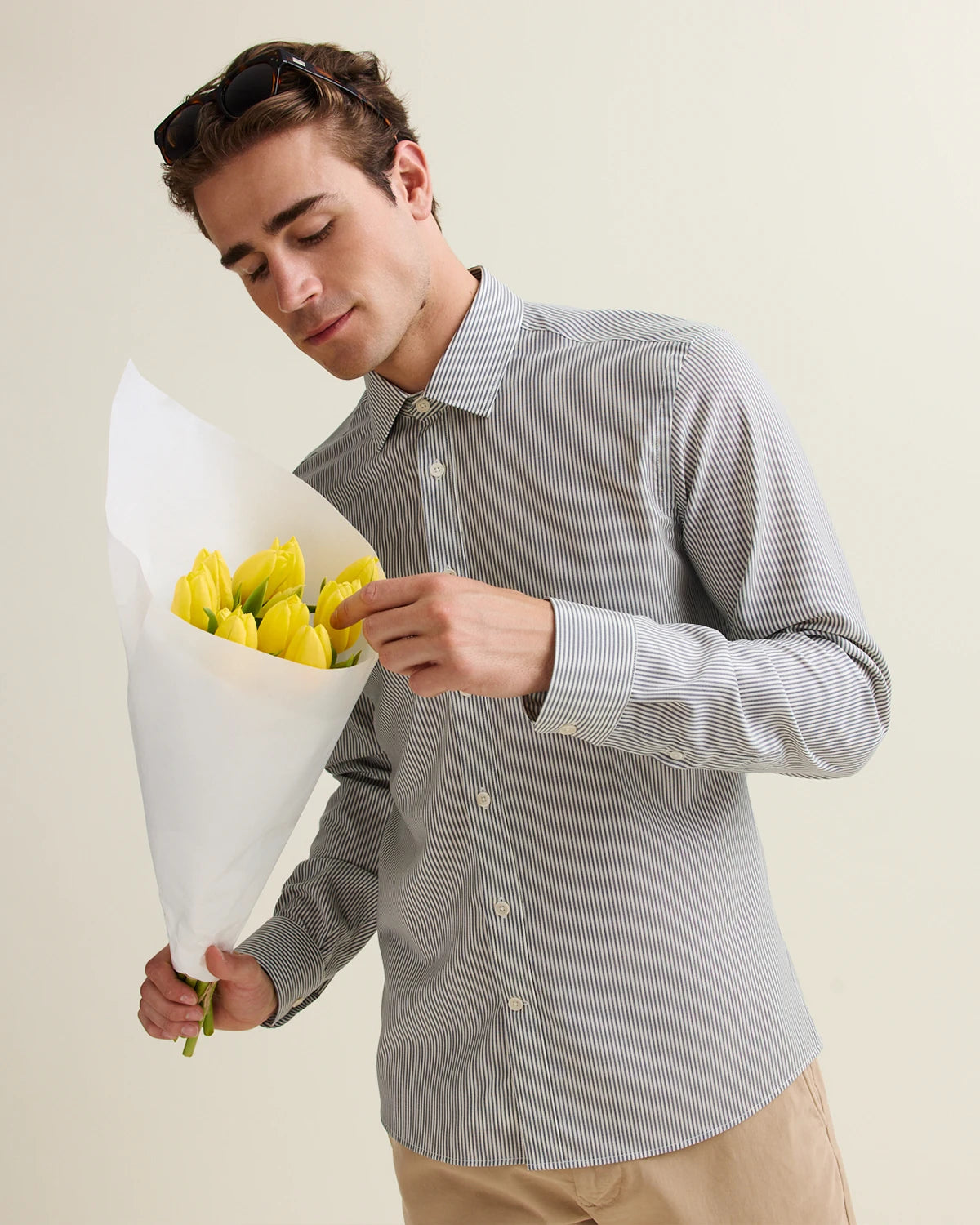 Man holding bouquet of tulips and wears a merino shirt with long sleeves in navy bengal stripe from Wolk