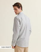 Man wearing a navy bengal striped shirt on a beige pants, view from the back