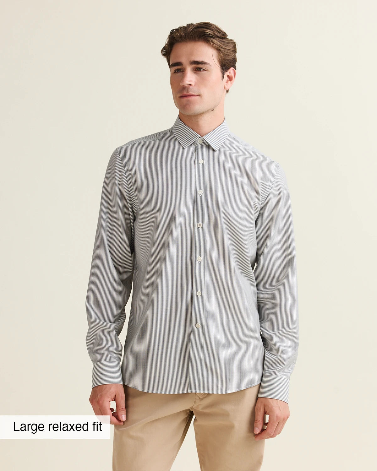 Front view of a man wearing a navy bengal striped merino shirt with a large relaxed fit label from Wolk