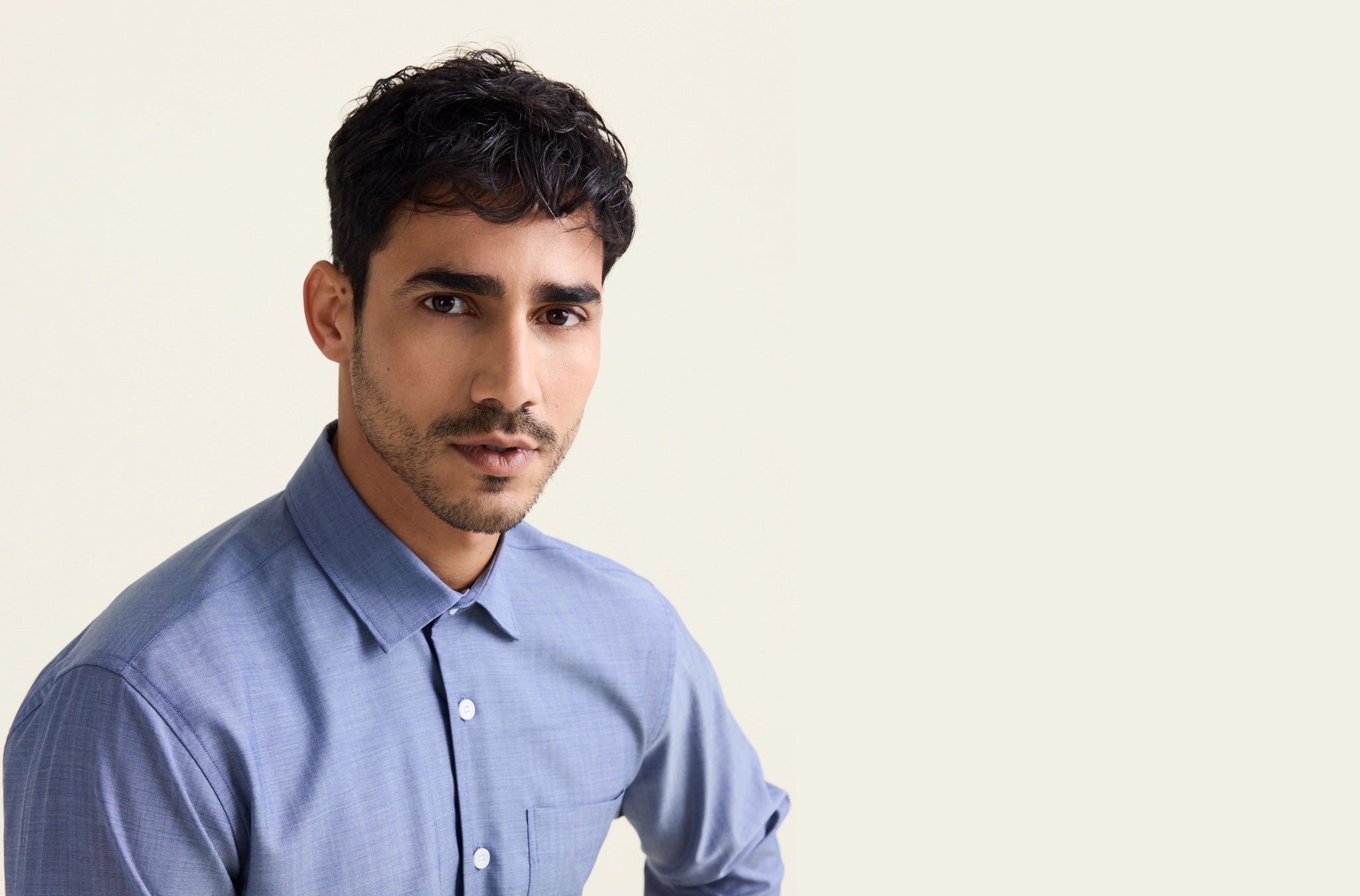 Man wears a light blue denim shirt in merino wool with chest pocket