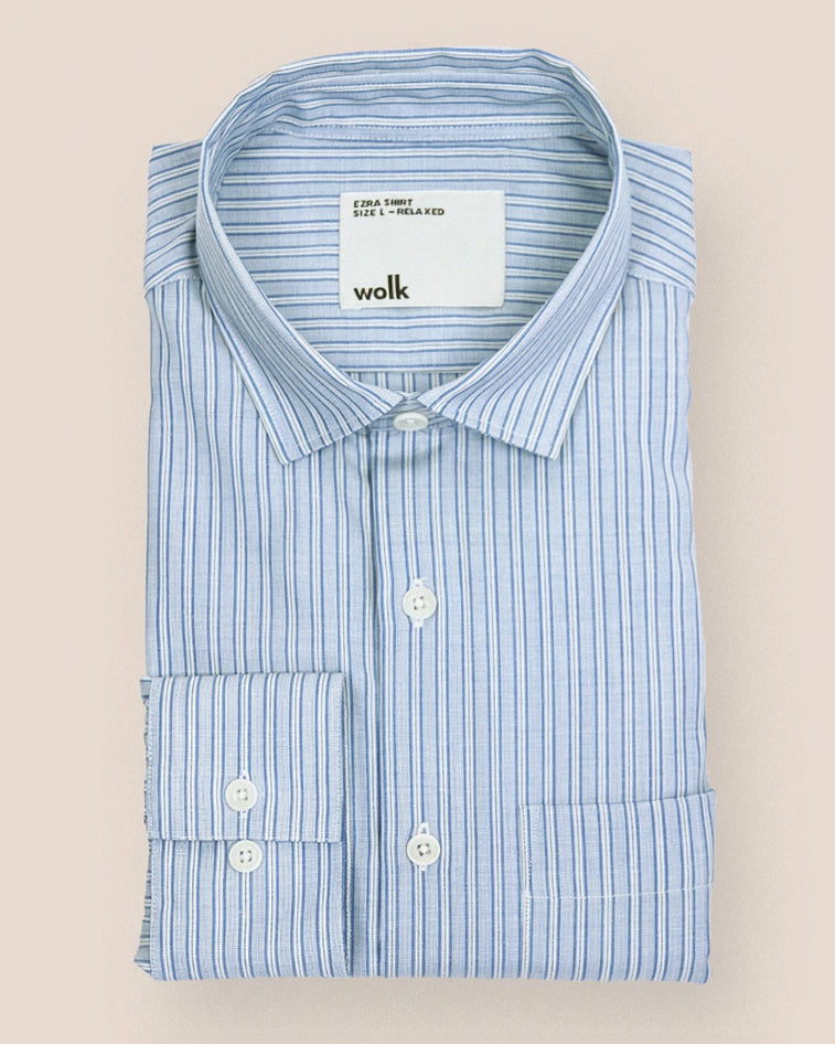 Folded blue striped merinowool shirt with a visible Wolk brand label on a beige background