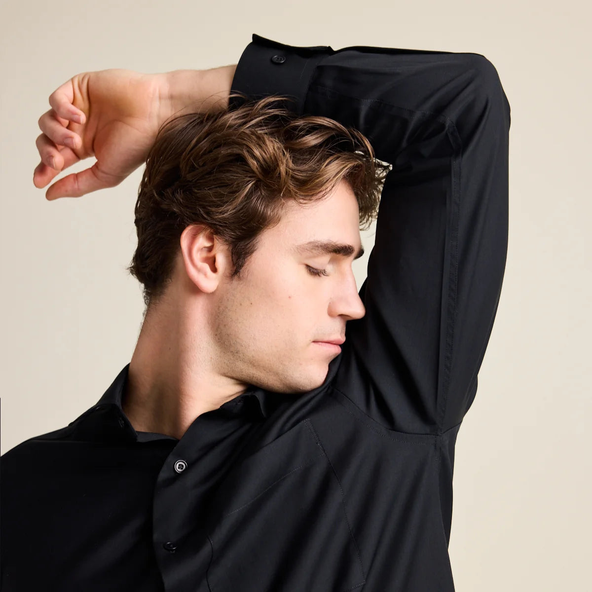 Man smelling his armpit and wearing a odour resistant merino wool black shirt from Wolk