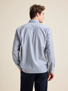 Back view of model wearing a blue with striped merino wool shirt on navy pants.