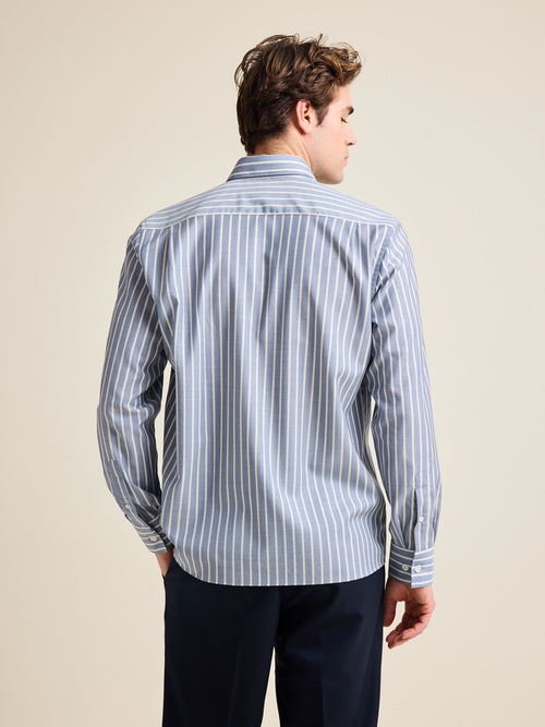Back view of model wearing a blue with striped merino wool shirt on navy pants.