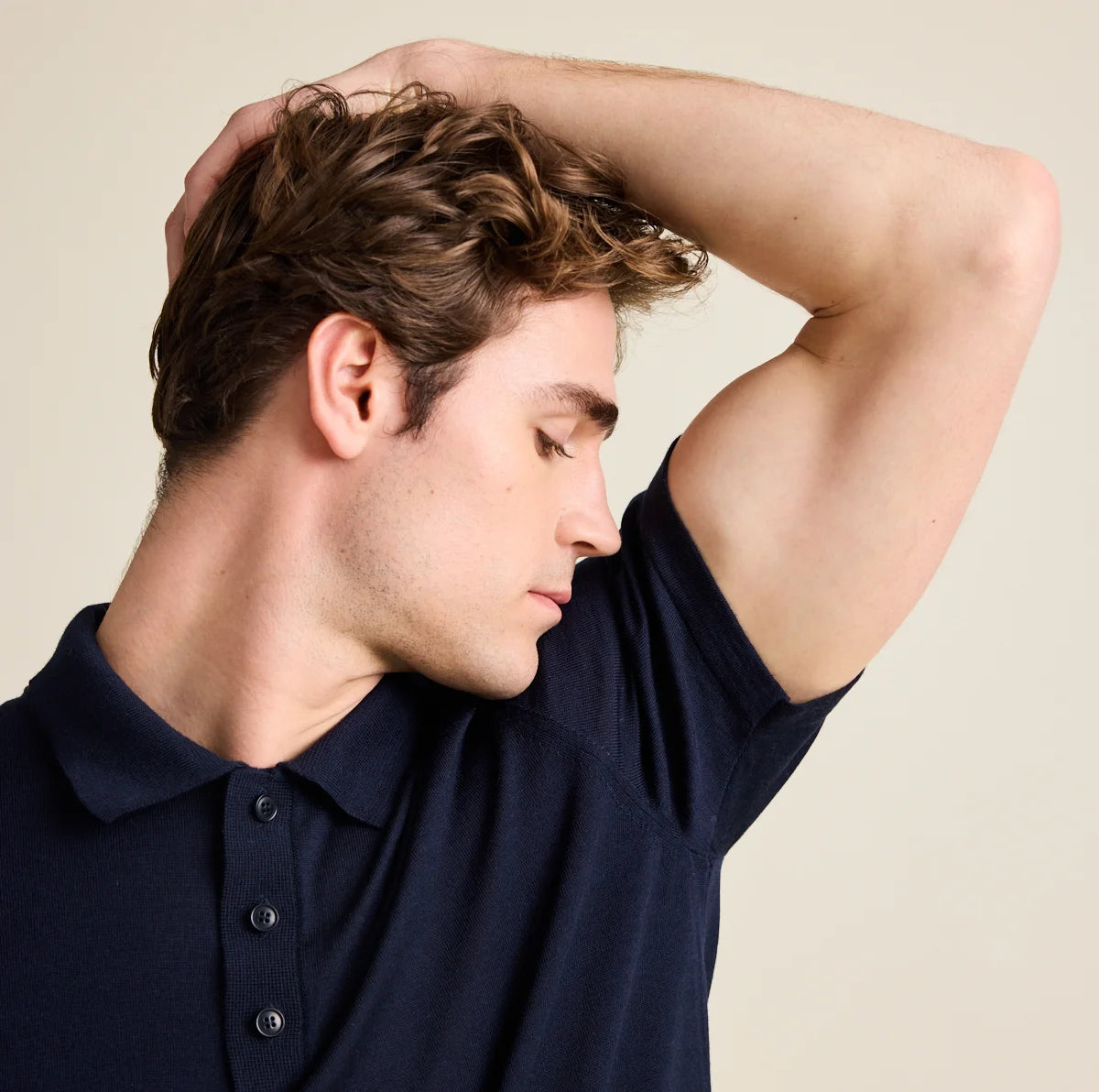 Man wearing a navy blue polo shirt odour resistant against a beige background