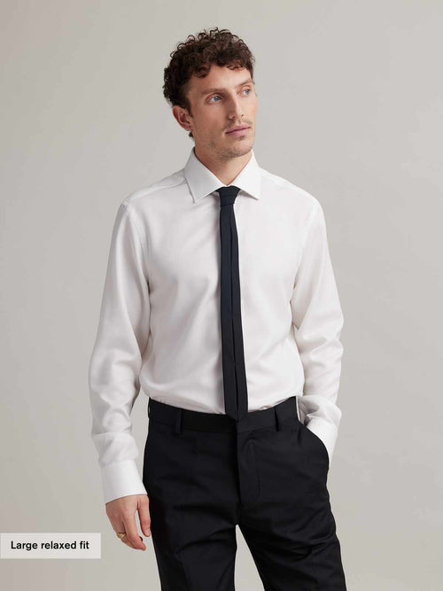 Man wears a white merino wool  formal shirt with twill fabric and English spread collar with black tie in relaxed fit