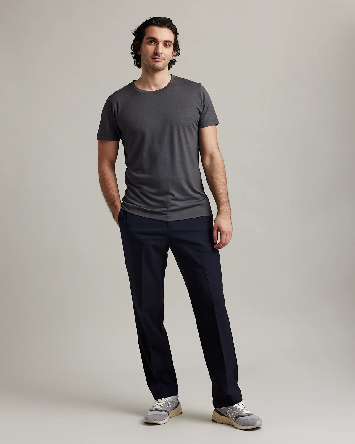 Man wearing a dark gray merino t-shirt and black pants in the studio
