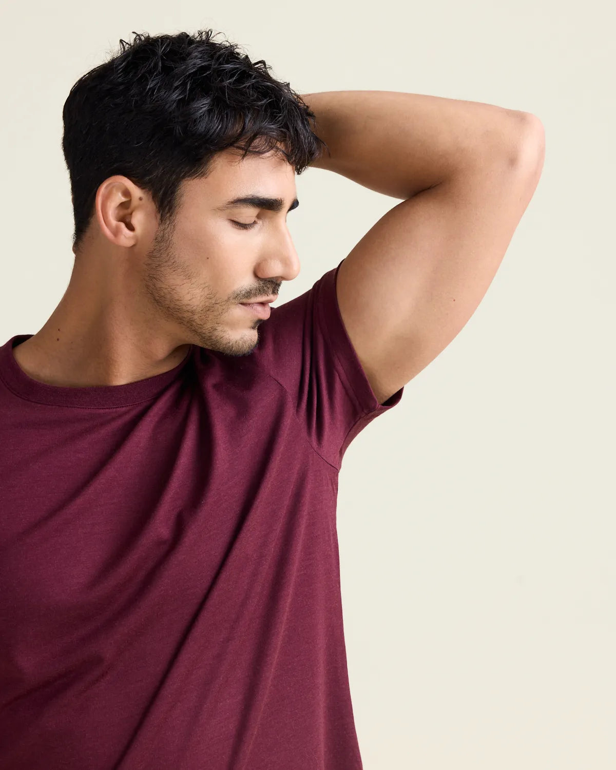 man smells his fresh armpit wearing a burgondy coloured merino tshirt from Wolk