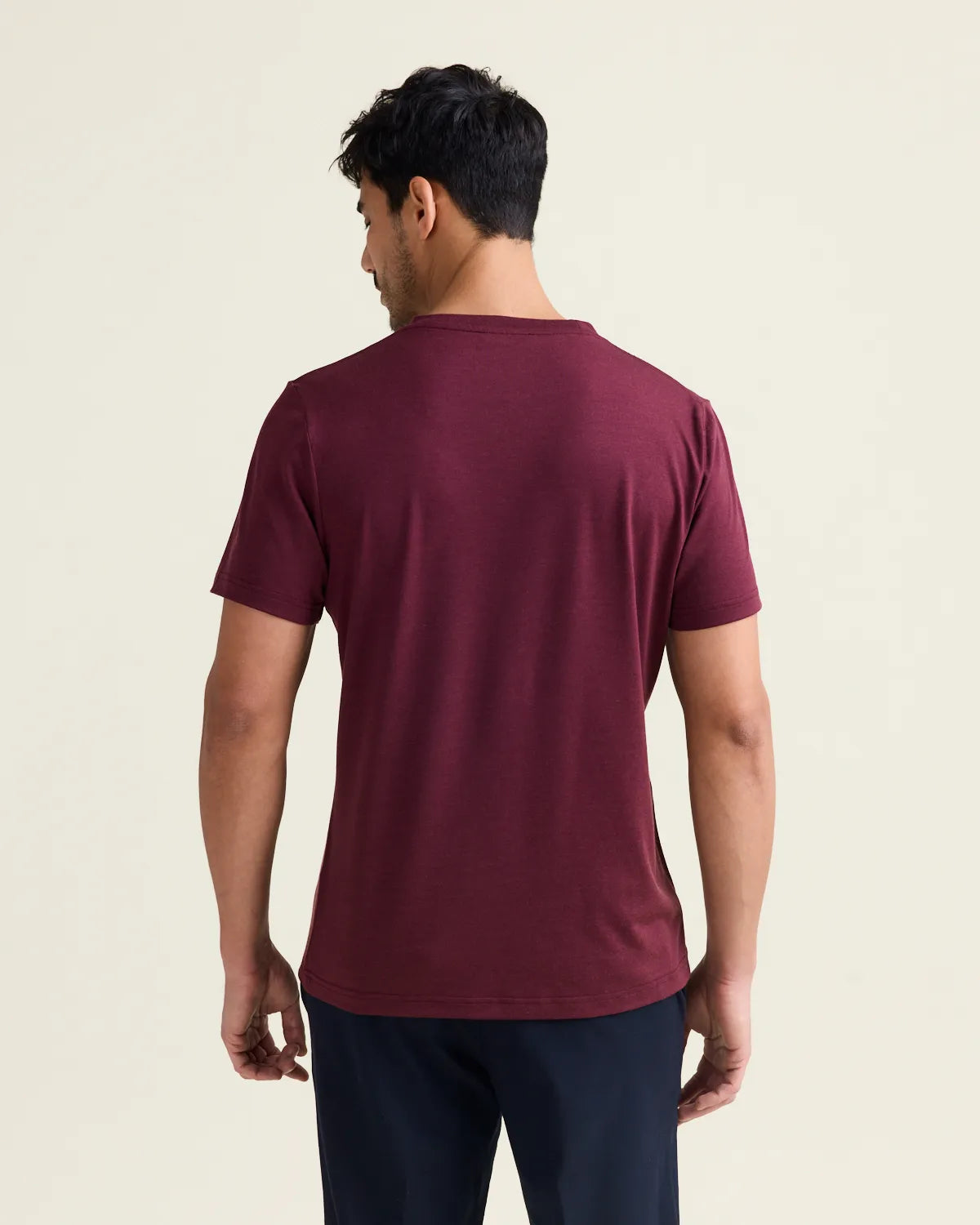 back view of a man with a burgundy merino tshirt in studio setting