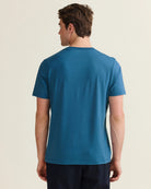 Back view of a man wearing a blue merino wool T-shirt with short sleeves