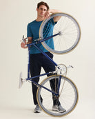 Man holding a bike and wears a blue merino wool T-shirt 