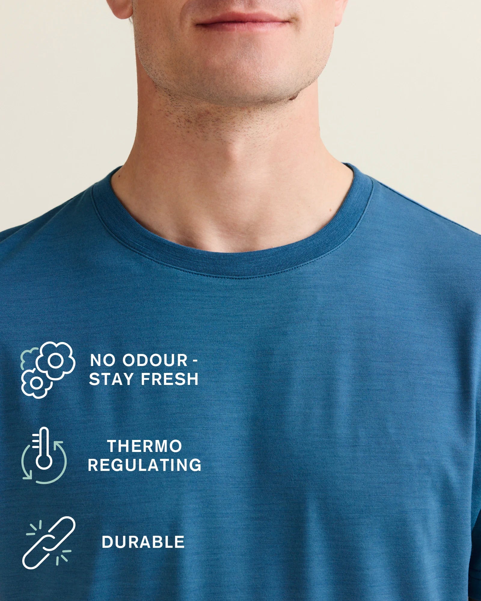 Wolk's blue merino T-shirt collar detail with benefit icons: no odour, thermo-regulating and durable.