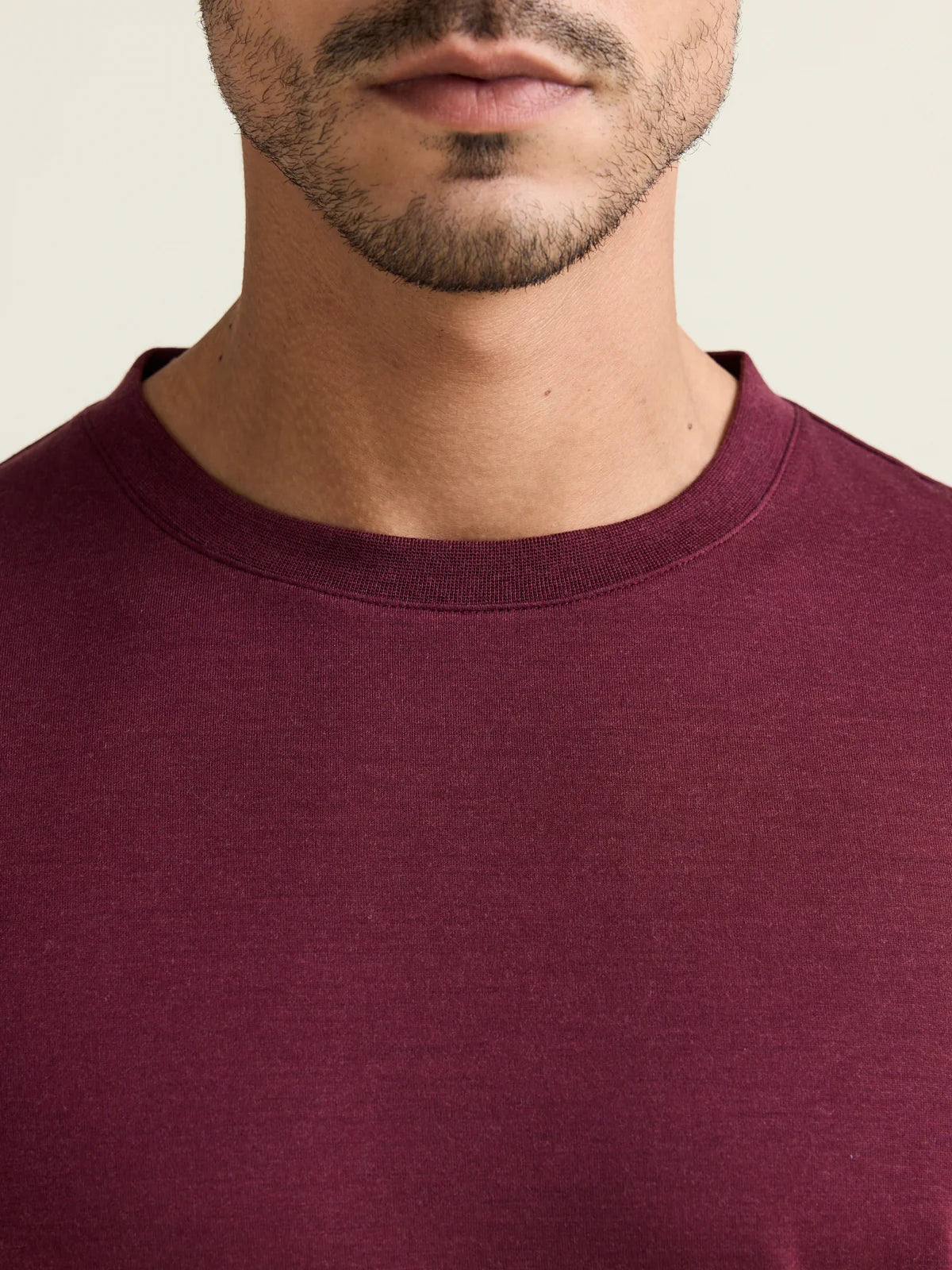 Close up of the crew-neck collar from a men’s merino wool T-shirt in burgundy from the brand Wolk.