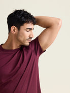 Model smells his armpits wearing a merino wool T-shirt with short sleeves in burgundy color with crew neck from Wolk