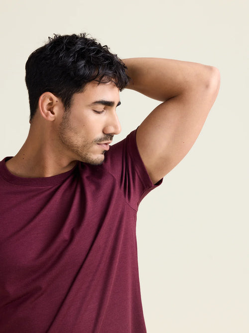 Model smells his armpits wearing a merino wool T-shirt with short sleeves in burgundy color with crew neck from Wolk