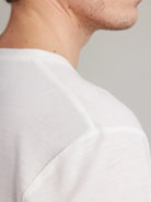 Close-up of a person wearing a white shirt against a neutral background