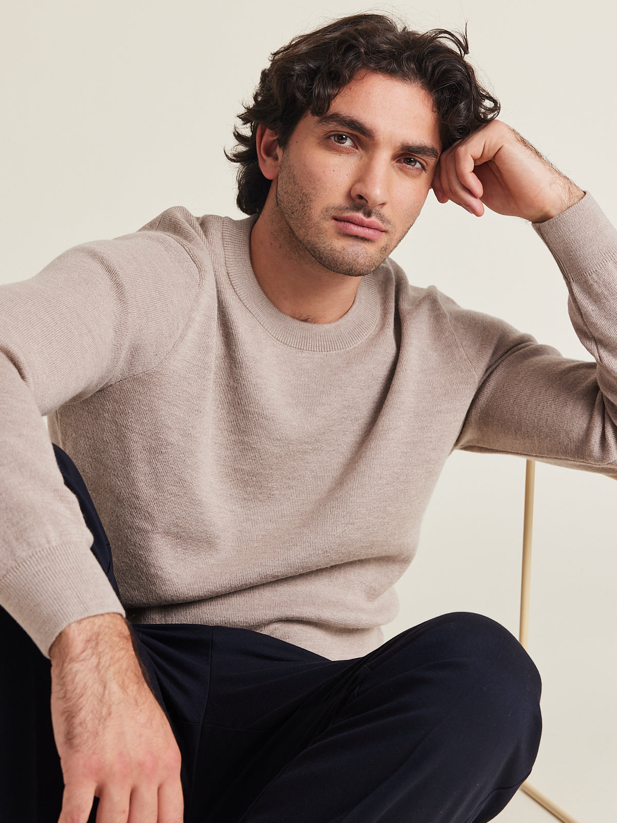 Man wears a 100% merino wool sweater in taupe color on a navy trousers round collar mid weight all year round pullover