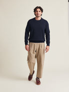 Man wears a merino wool sweater in dark navy color on a beige trousers 