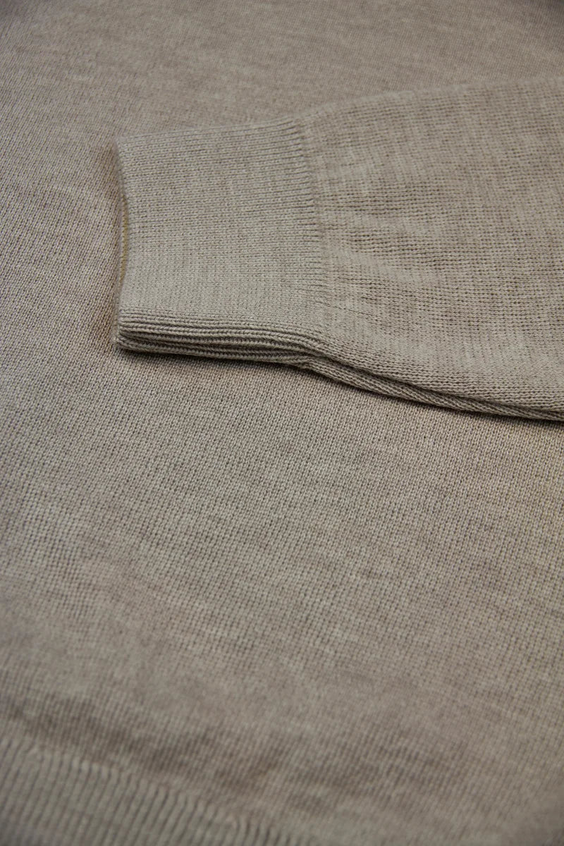 Folded beige merino wool sweater with a close up of the half milano stitch