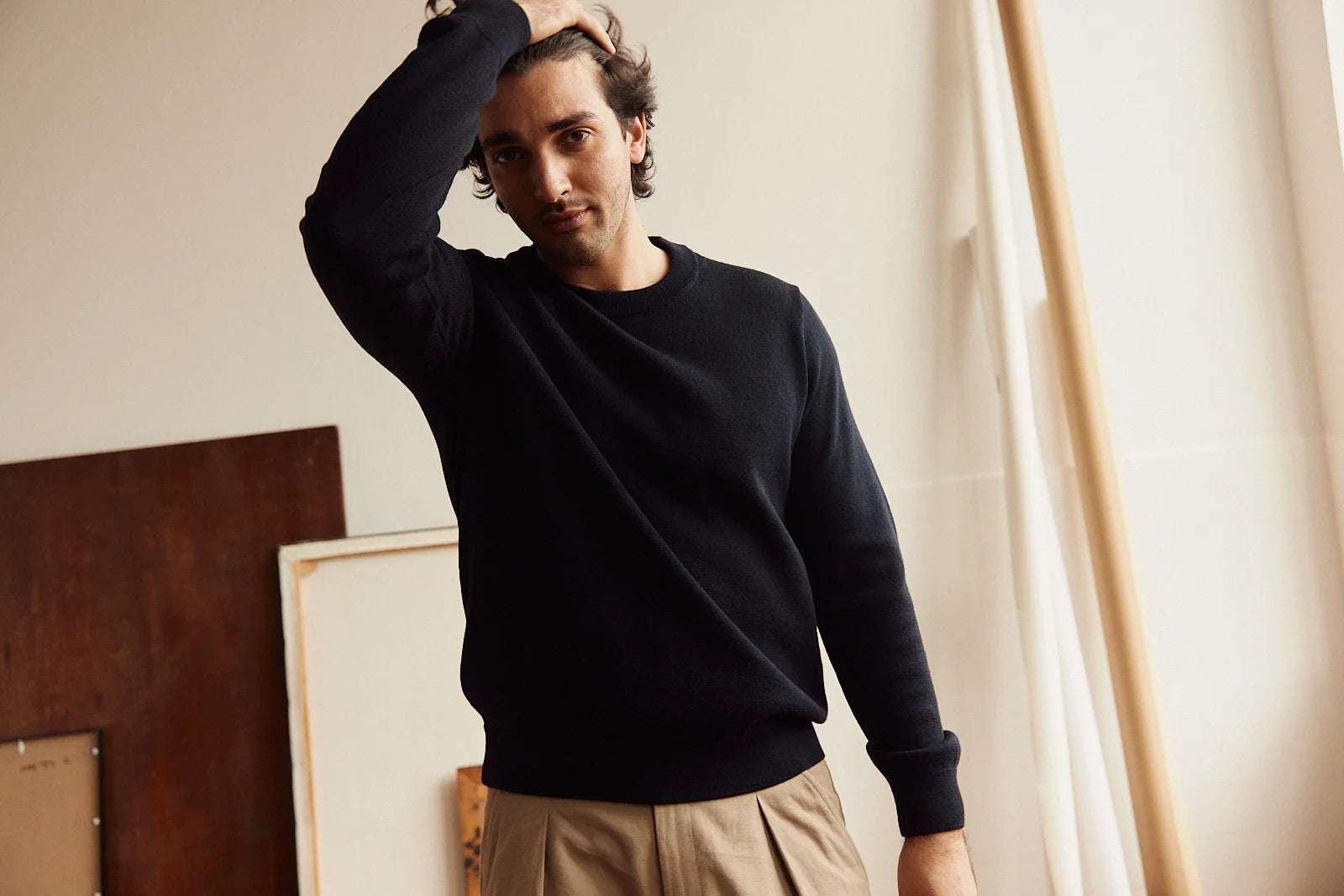 Man wearing a dark navy merino wool  sweater and beige pants in an indoor setting