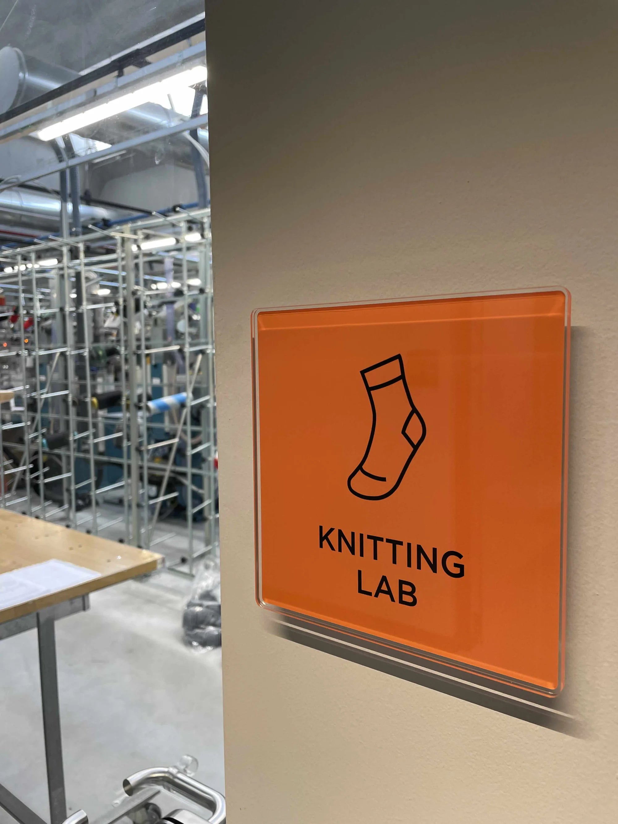 Orange sign with a sock icon and 'Knitting Lab' text on a wall.