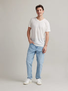 Male model wears a white merino wool T-shirt with V neck on a light blue denim jeans.