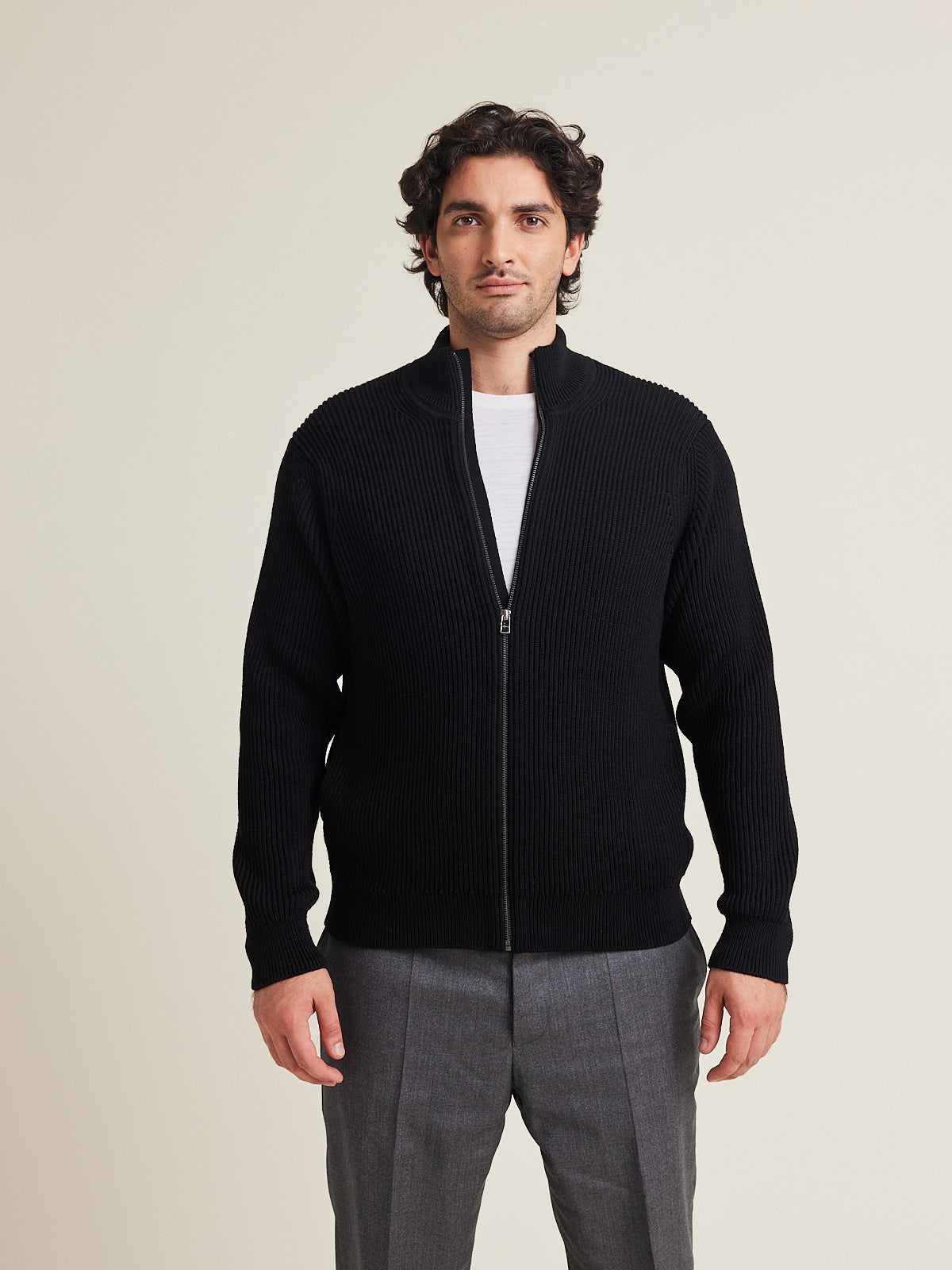Man wears a full zip merino wool cardigan in black color and sidepockets from Wolk