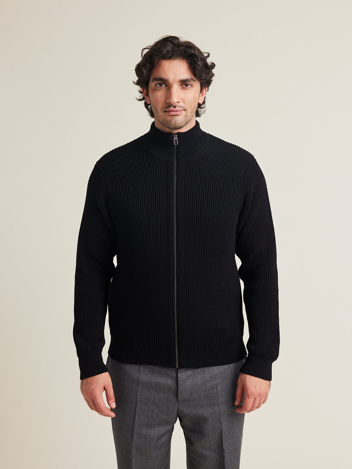 men wears a 100% merino wool knit vest in half cardigan knit with high collar in black color made in heavy weight superfine responsible merino wool