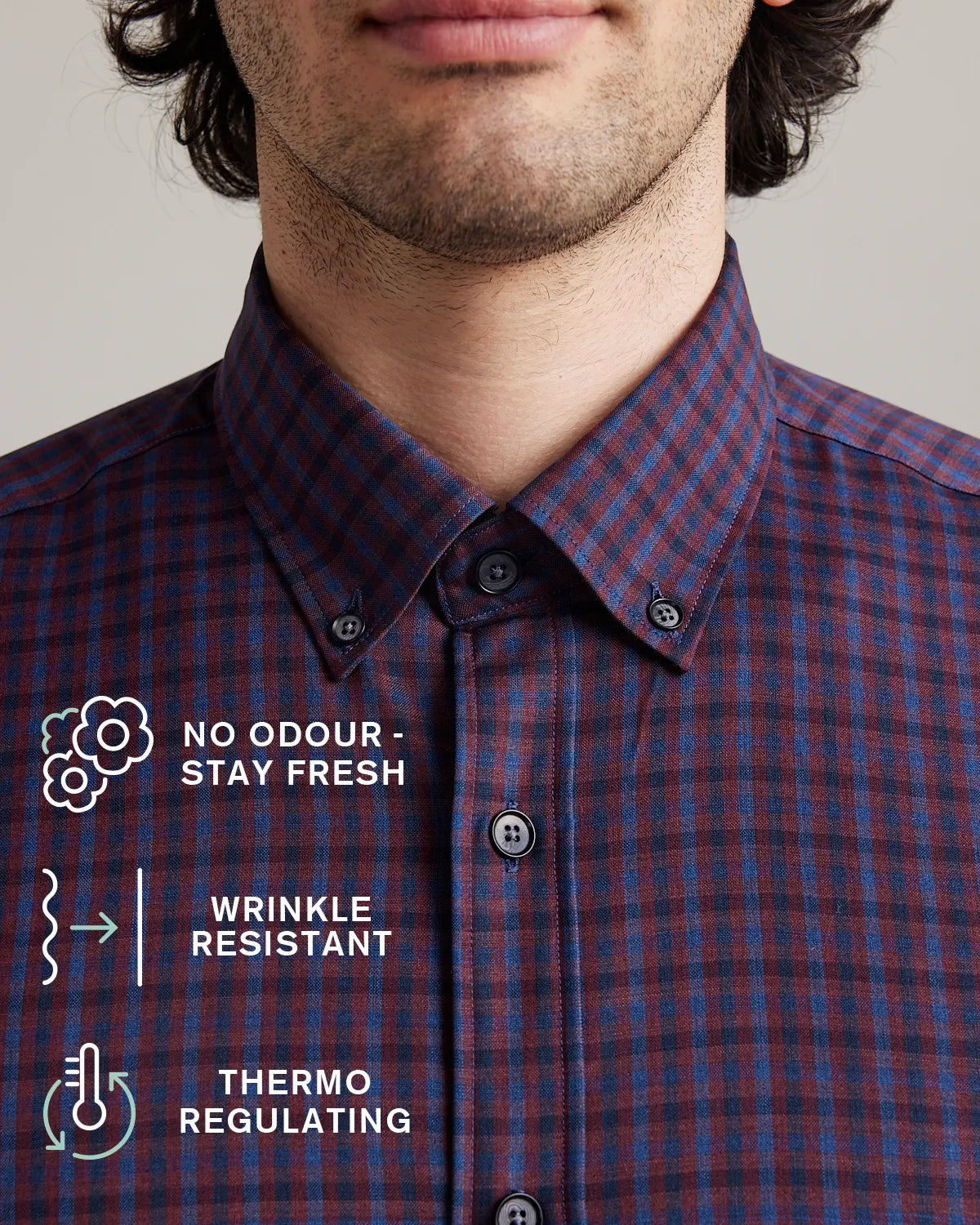 Man wearing a burgundy checkered merino button-down with text on features.