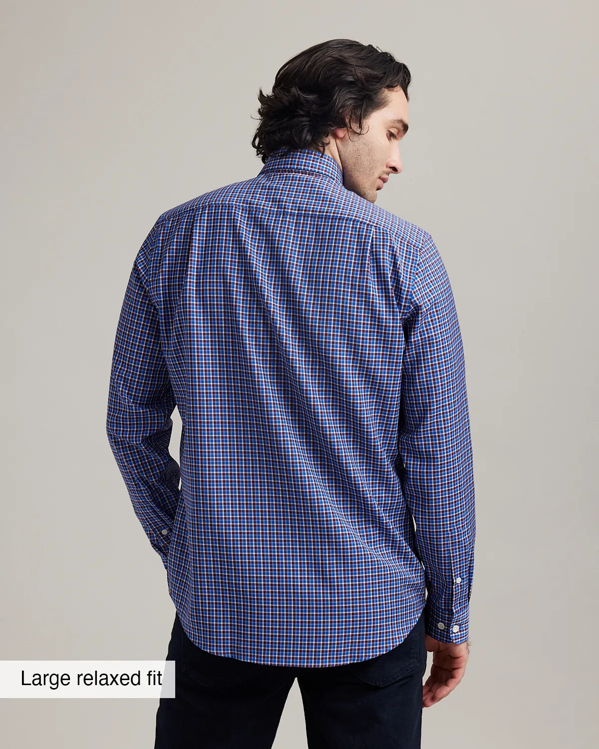 Back view of a man wearing a blue/red checkered merino wool button down shirt in relaxed fit
