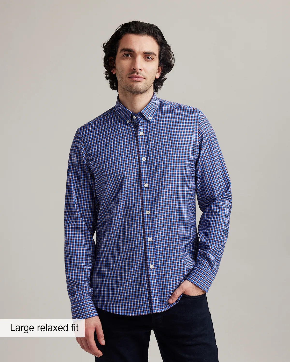 Man wearing a blue/red checkered merino wool button down shirt against a gray background