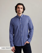 Man wearing a blue/red checkered merino wool button down shirt against a gray background