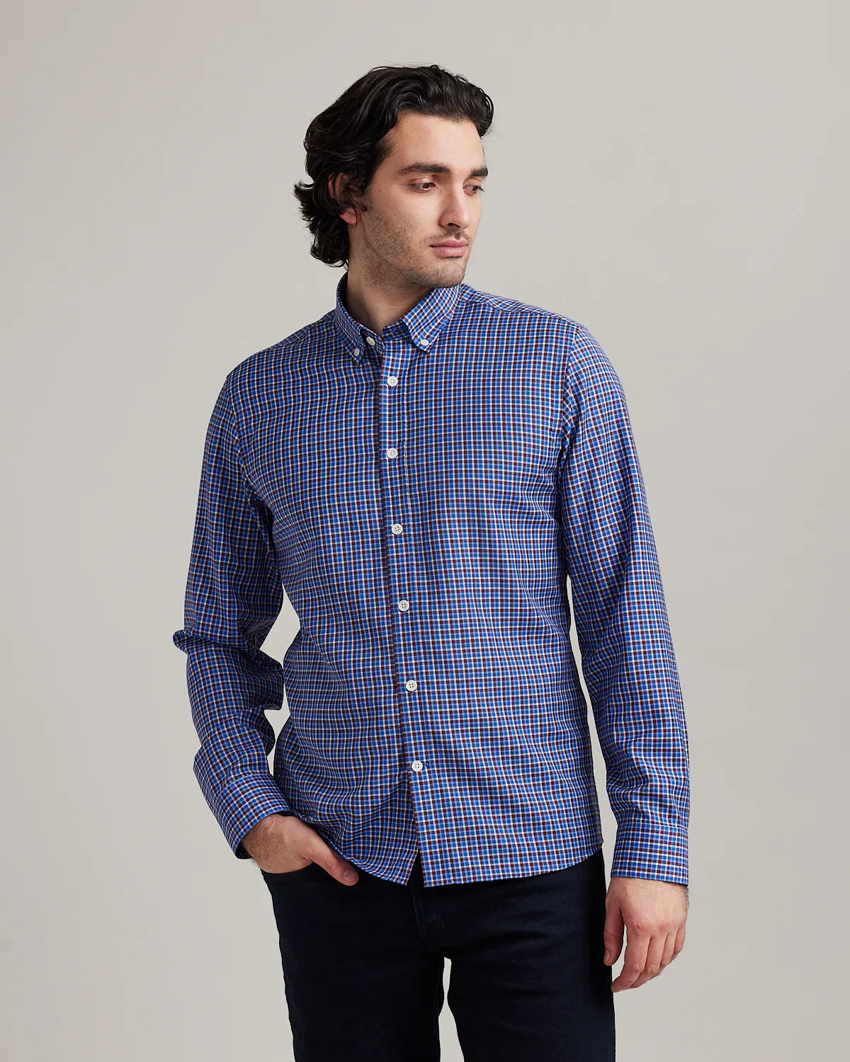 Man wearing a blue/red checkered merino wool button down shirt on a gray background
