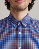 Close-up of a person wearing a blue/red checkered merino wool button down shirt
